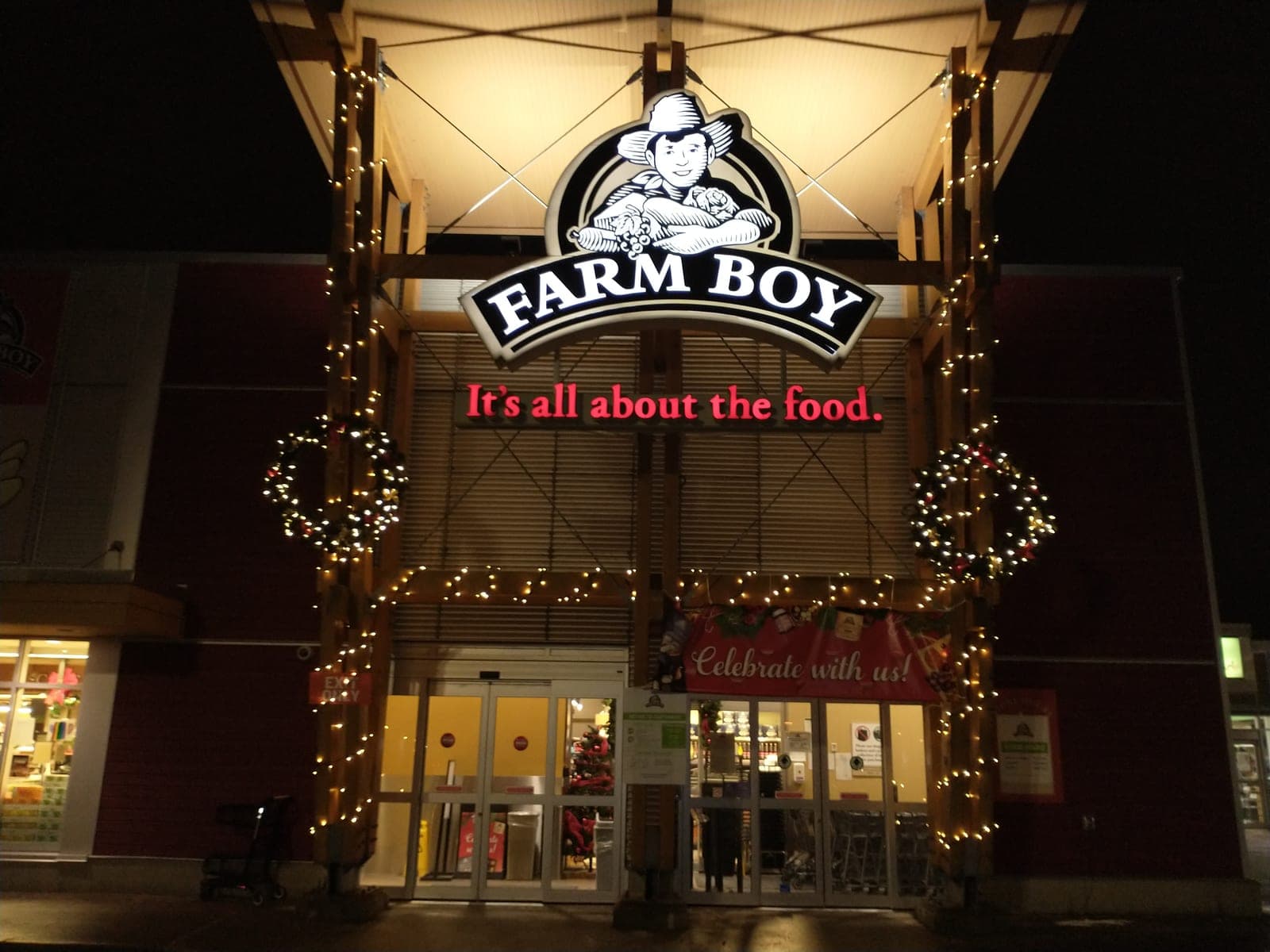 Commercial storefront entrance with lit Christmas wreaths and warm-white garland-wrapped columns