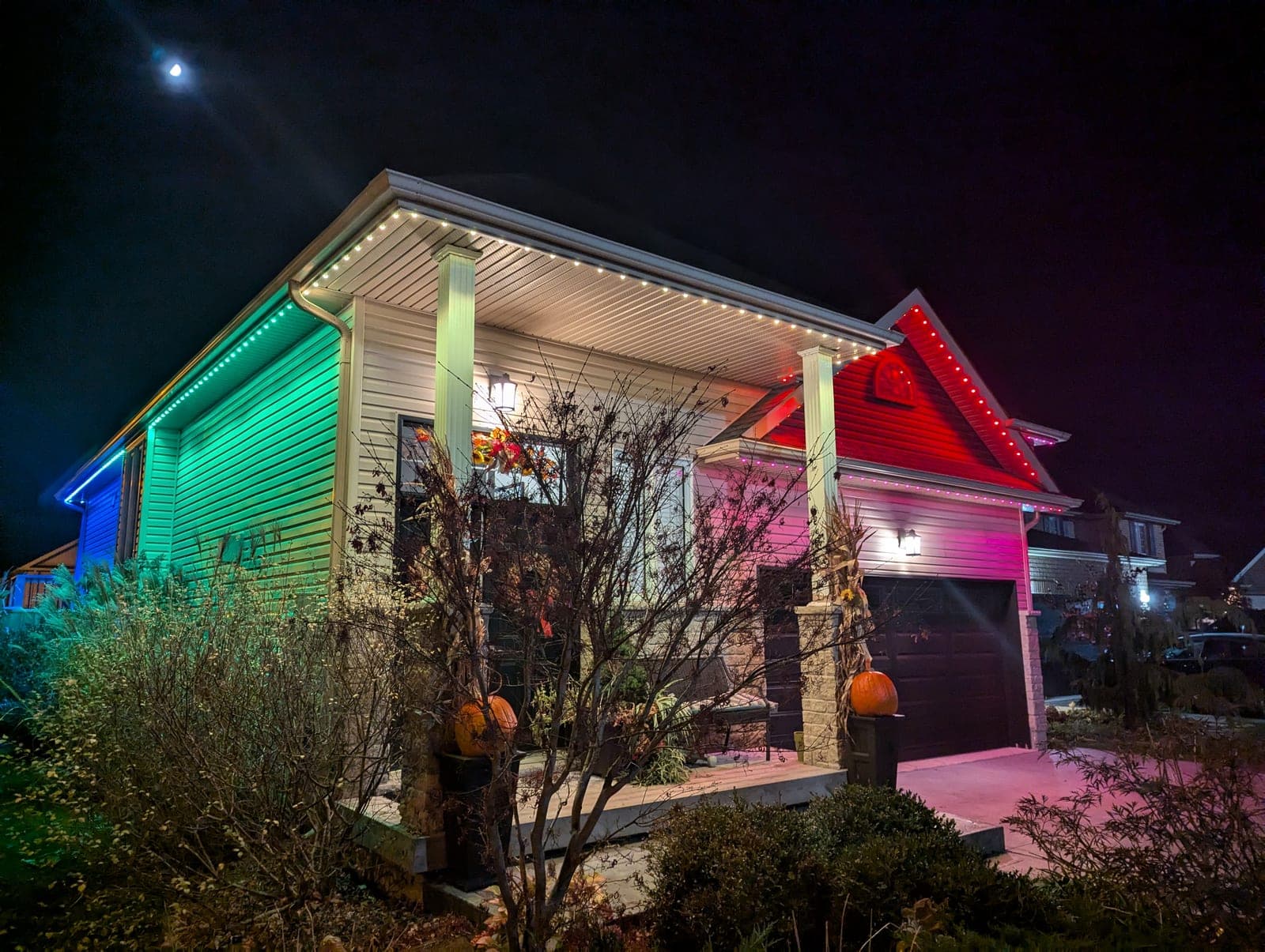 Home dramatically lit half green and half red with RGB permanent LED holiday lighting