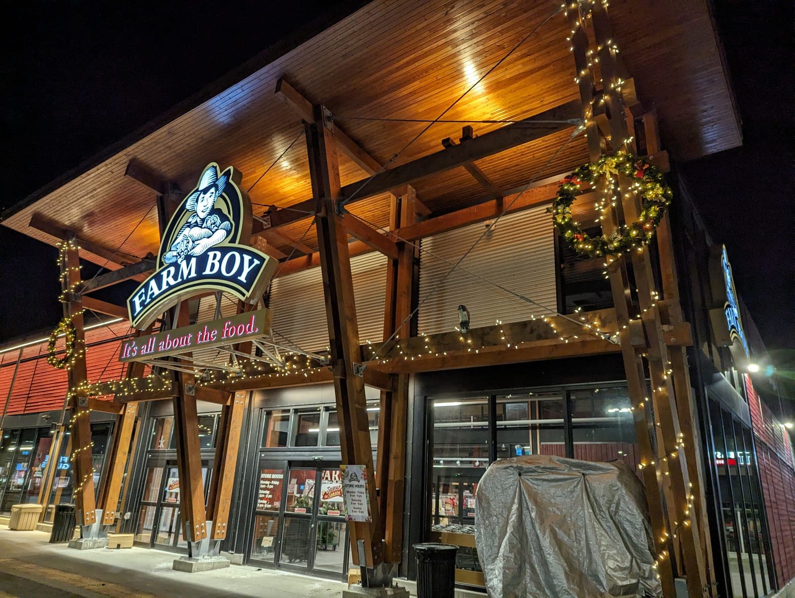 Commercial storefront timber facade wrapped in warm-white Christmas string lights at night